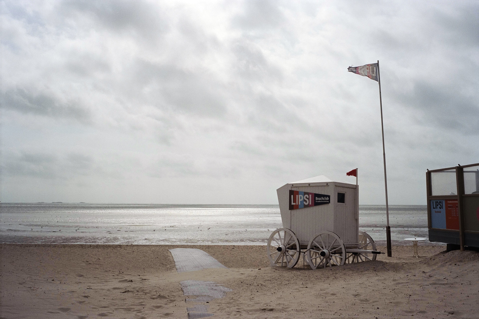 Ein Sandstrand mit einer Strandhütte und einer Flagge.